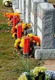 three red flickering LED candles graveside with flowers